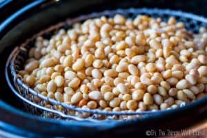 Cooking the soaked soybeans in a slow cooker by steaming them in a basket above some water.