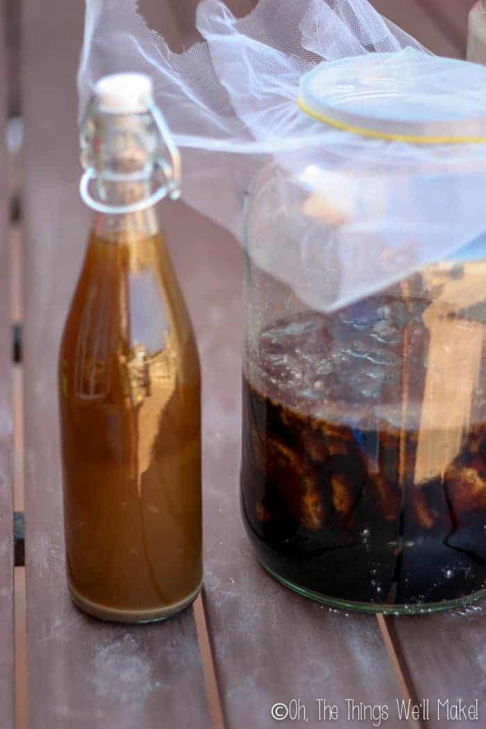 A bottle of homemade soy sauce next to a jar of fermented soy in brine.