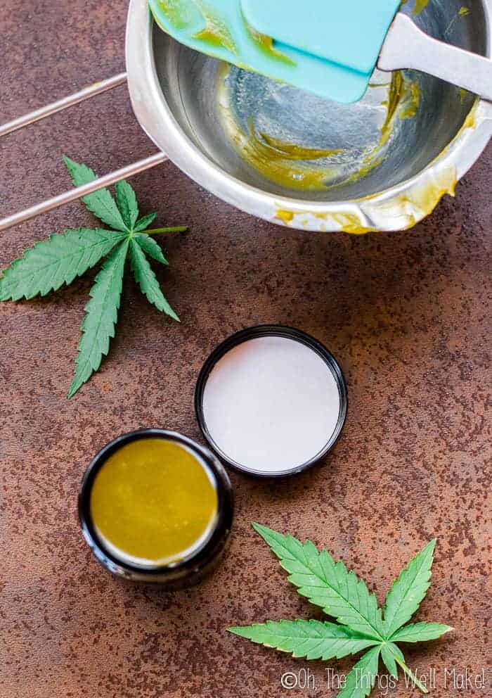 A homemade CBD salve on a countertop with a double boiler insert and a spatula that are covered with 