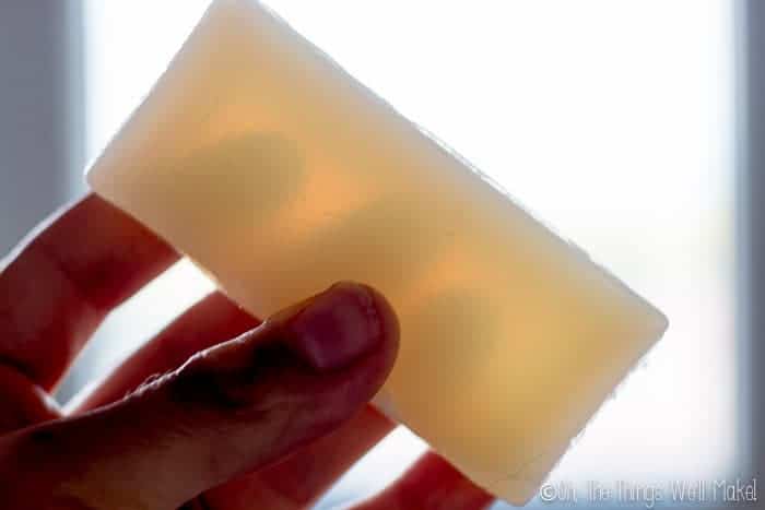 Holding up a homemade vegan glycerin soap to the light to show its translucency.