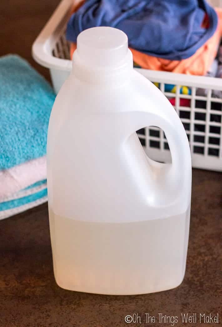 A bottle of homemade laundry detergent with some clean clothes.