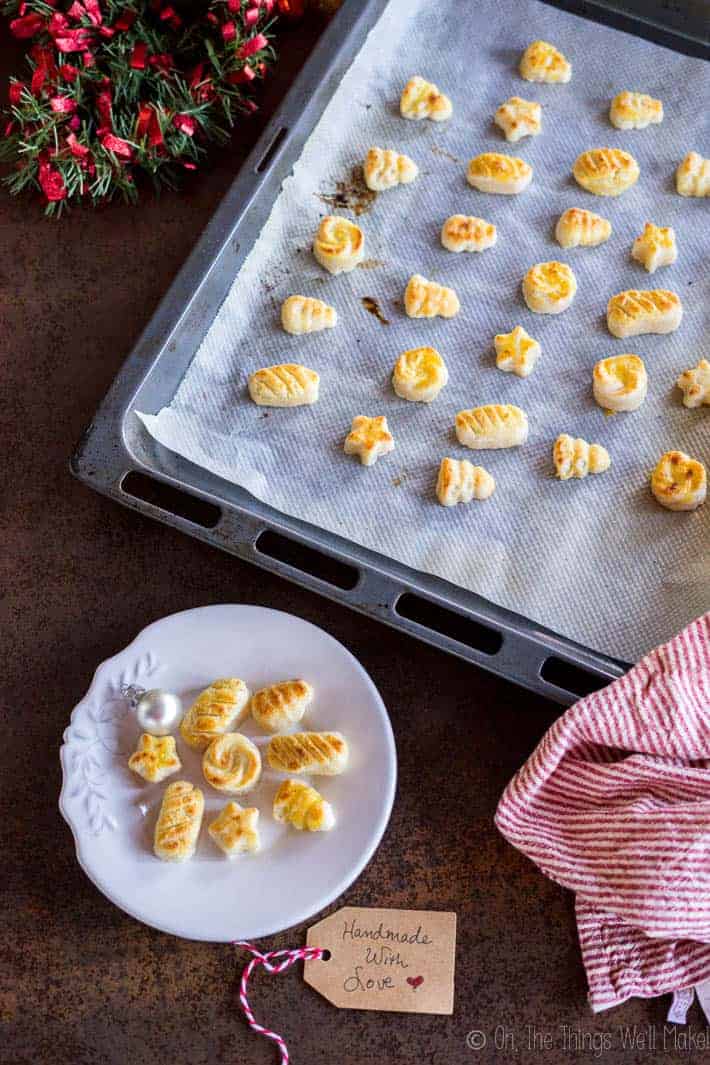 Homemade marzipan figures on a baking sheet and on a plate, surrounded by Christmas decorations.