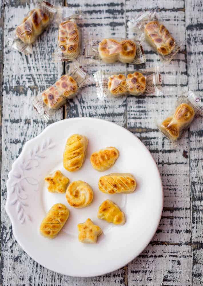 Homemade marzipan figures on a plate next to wrapped figuras de mazapán from the store.