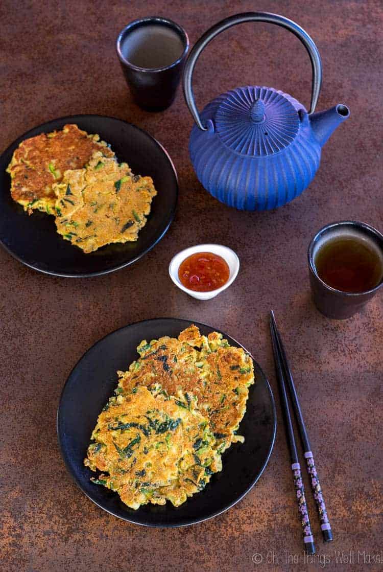 Overhead view of 4 zucchini pancakes, or hobakjeon, with some sweet and sour sauce.