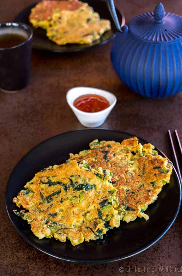 closeup of two zucchini pancakes with a couple more in the background.