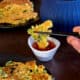 dipping a piece of zucchini pancakes (hobakjeon) into sweet and sour sauce with chopsticks.