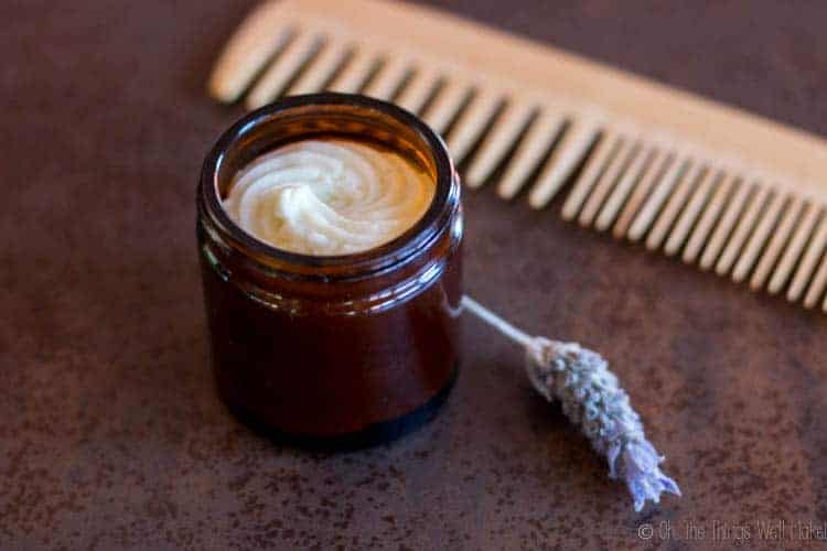 Homemade hair butter in a har with a lavender flower and a wooden comb