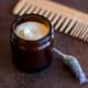 A jar filled with a homemade hair butter next to a sprig of lavender and a wooden comb