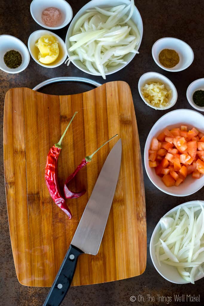 preparing the ingredients for the sauce. The chipotle peppers are on a bamboo cutting board.