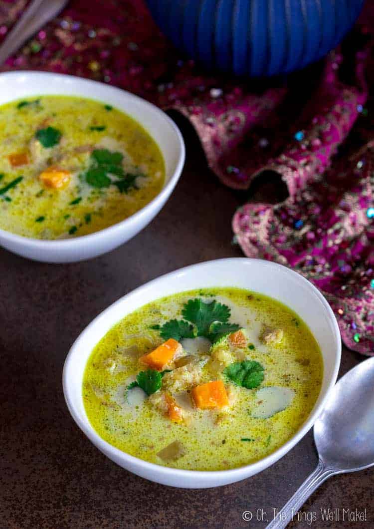 Closeup of a bowl of chicken Mulligatawny soup with visible carrots and cilantro garnish.