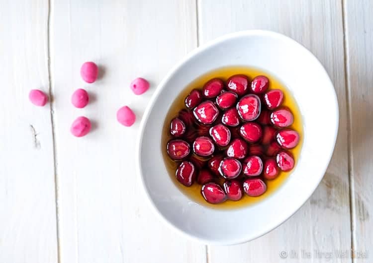 Overhead view of a bowl of homemade bright pink boba with some uncooked pink boba next to the bowl.