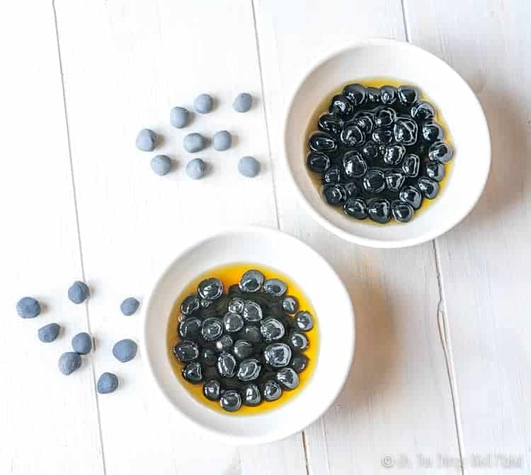 Two batches of homemade black boba, using different amounts of activated charcoal. One batch is slightly darker than the other batch.