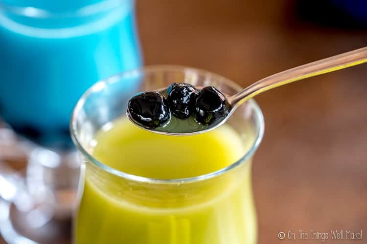 Homemade black boba being spooned out of a green matcha latte