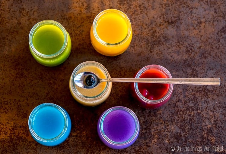 Overhead view of 6 glasses of naturally colores teas, the bottom two made with butterfly pea tea.