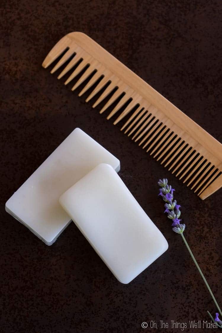 Overhead view of two conditioner bars next to a sprig of lavender and a wooden comb.