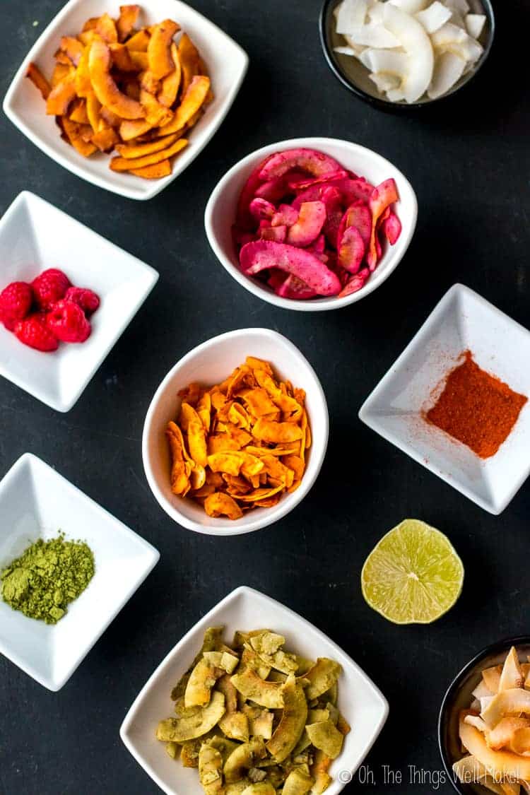 Overhead view of different varieties of seasoned coconut chips with their different flavorings in white bowls.