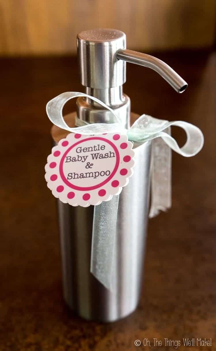 Stainless steel dispenser filled with a homemade baby wash and a label tied to it with ribbon.