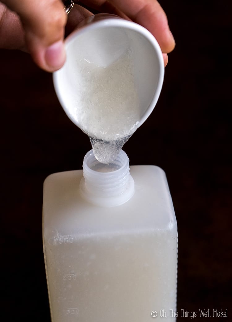 Pouring homemade baby wash gel into a plastic bottle