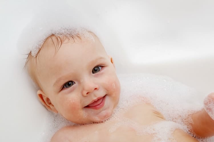 Foto of a baby in a bathtub with soap suds.