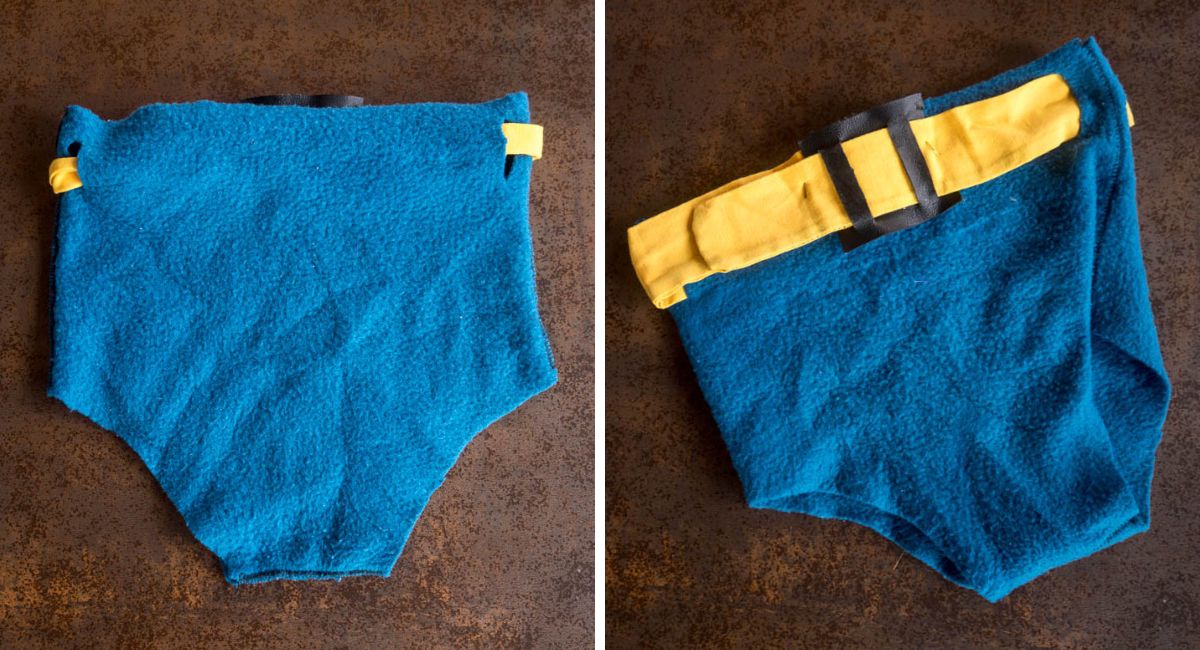 Front and back views of homemade blue fleece Batman trunks, showing the yellow fabric belt and black buckle.