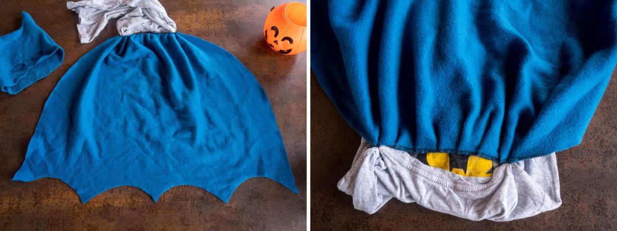 Homemade blue fleece Batman cape with a scalloped bottom edge, shown laid flat and gathered at the shoulders of a Batman T-shirt.
