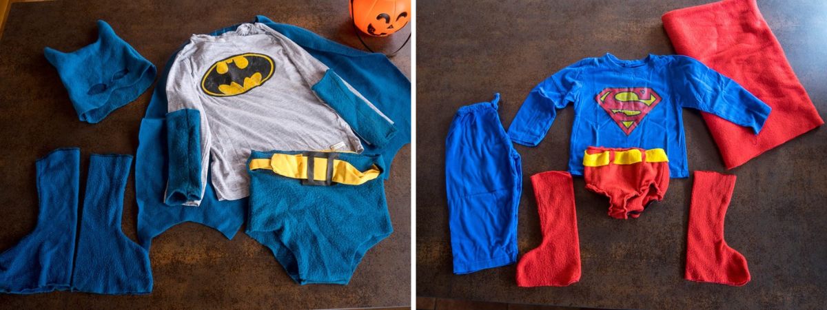 Homemade Batman and Superman costumes laid out side by side, showing fleece capes, boots, trunks, gloves, superhero shirts, and a Batman mask.