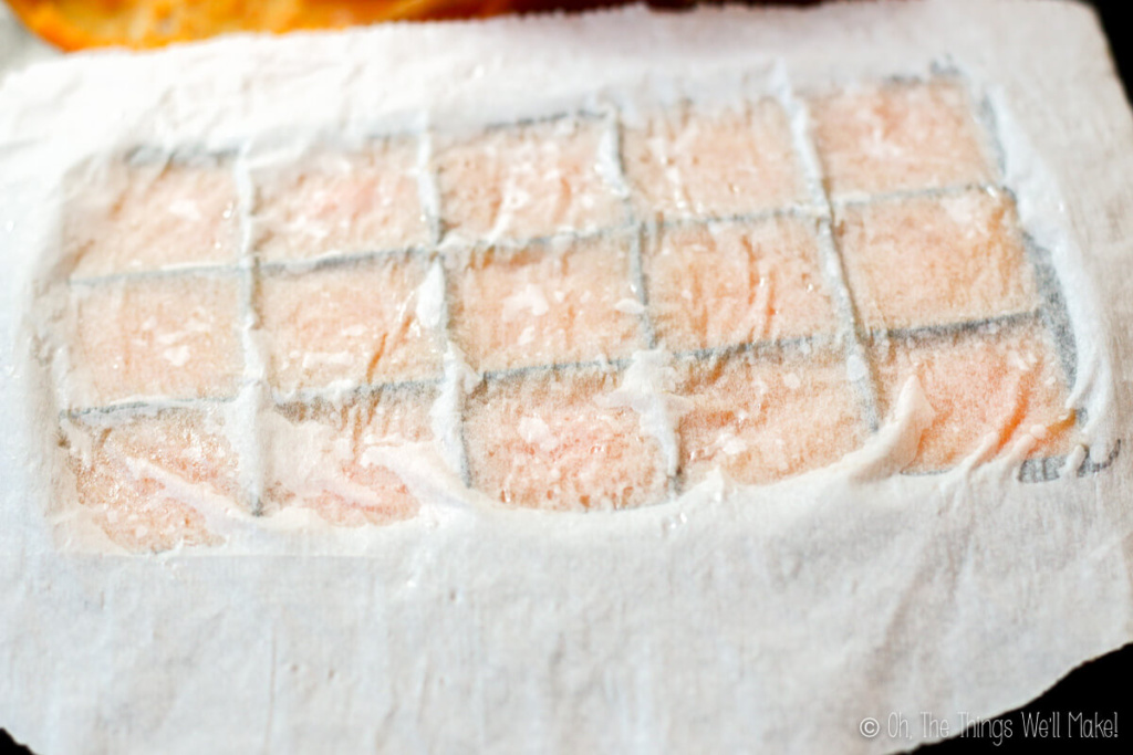 An ice cubre tray filled with pumpkin puree covered with parchment paper