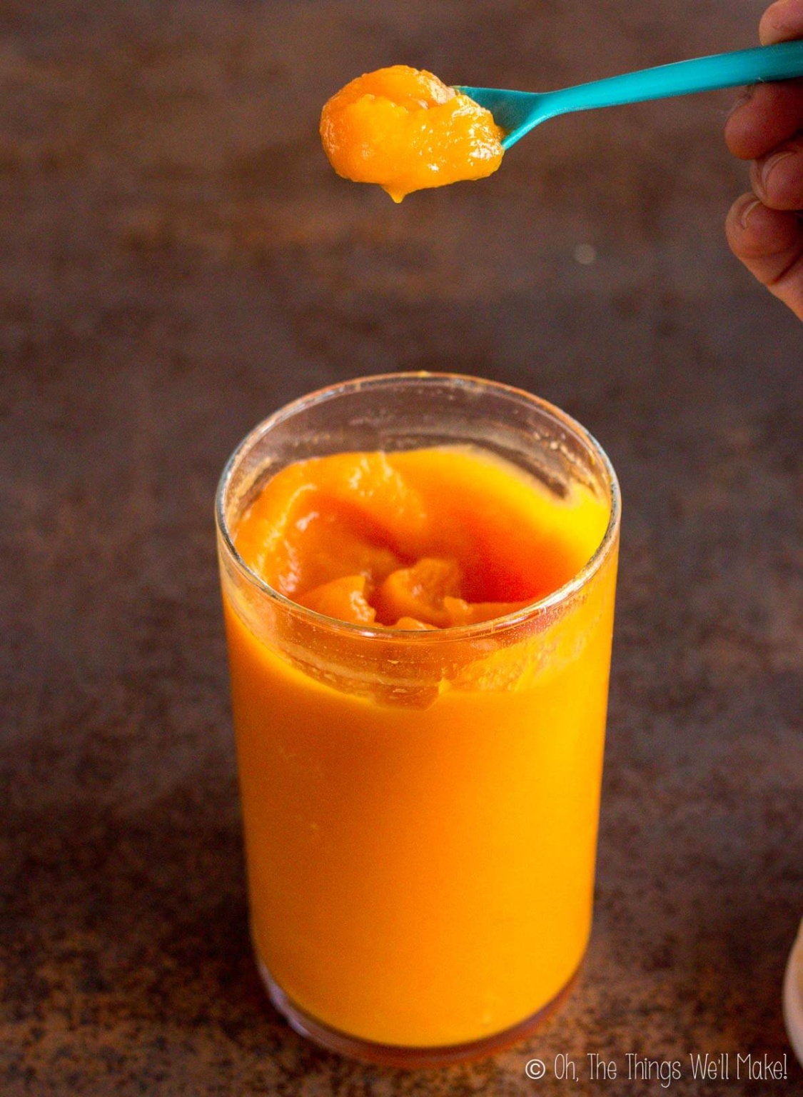 closeup of a spoonful of smooth pumpkin puree over a jar of it