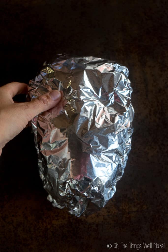 Pressing into an oval spheroid covered with aluminum foil to make eye socket shapes.