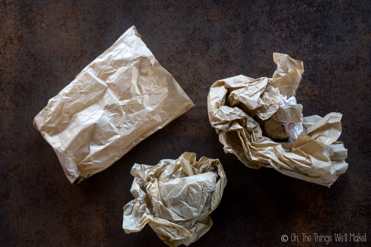 Top view of several scraps of paper from paper bags and brown tissue paper scrunched up into 3 parts.