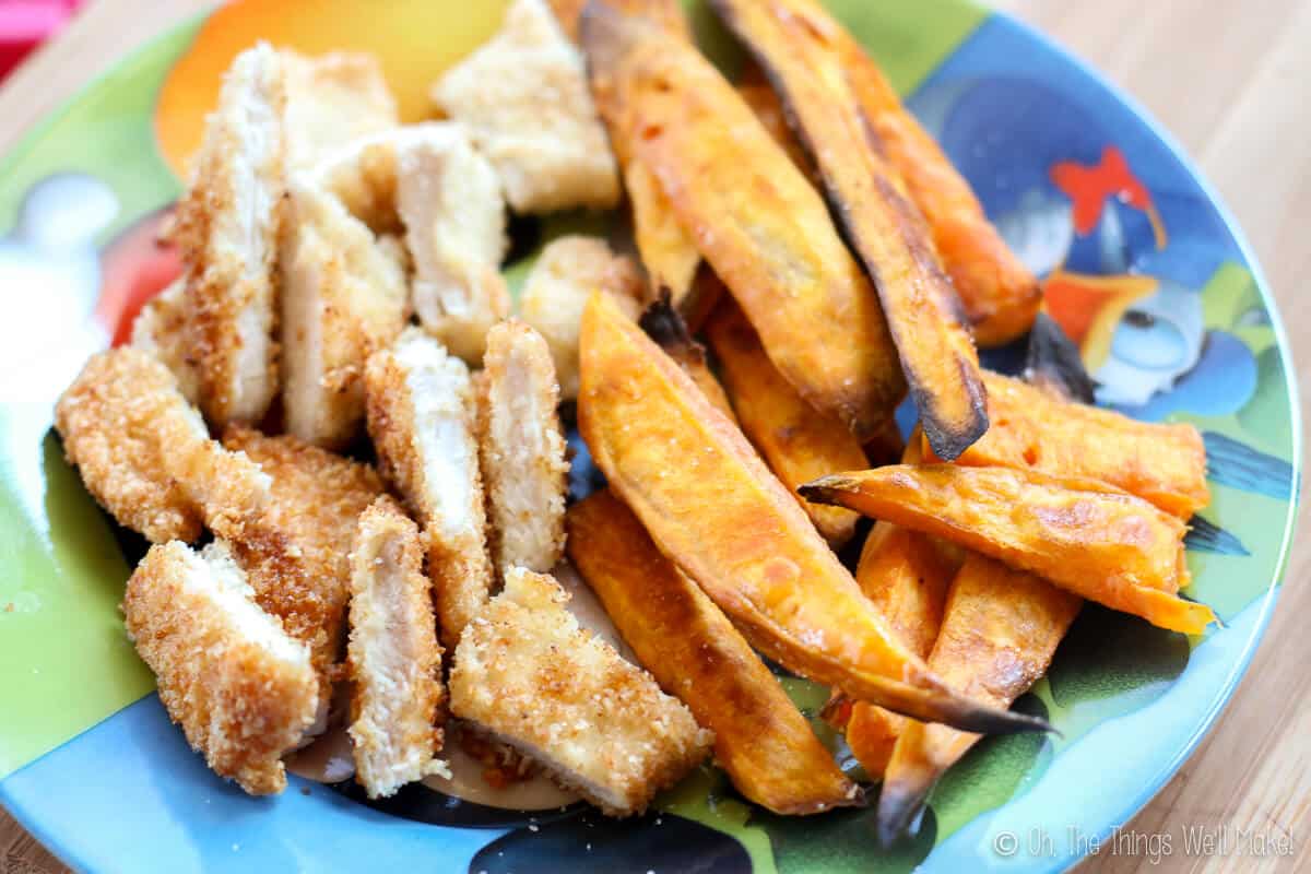 Close up of sliced homemade breaded chicken with baked sweet potato fries on the side.