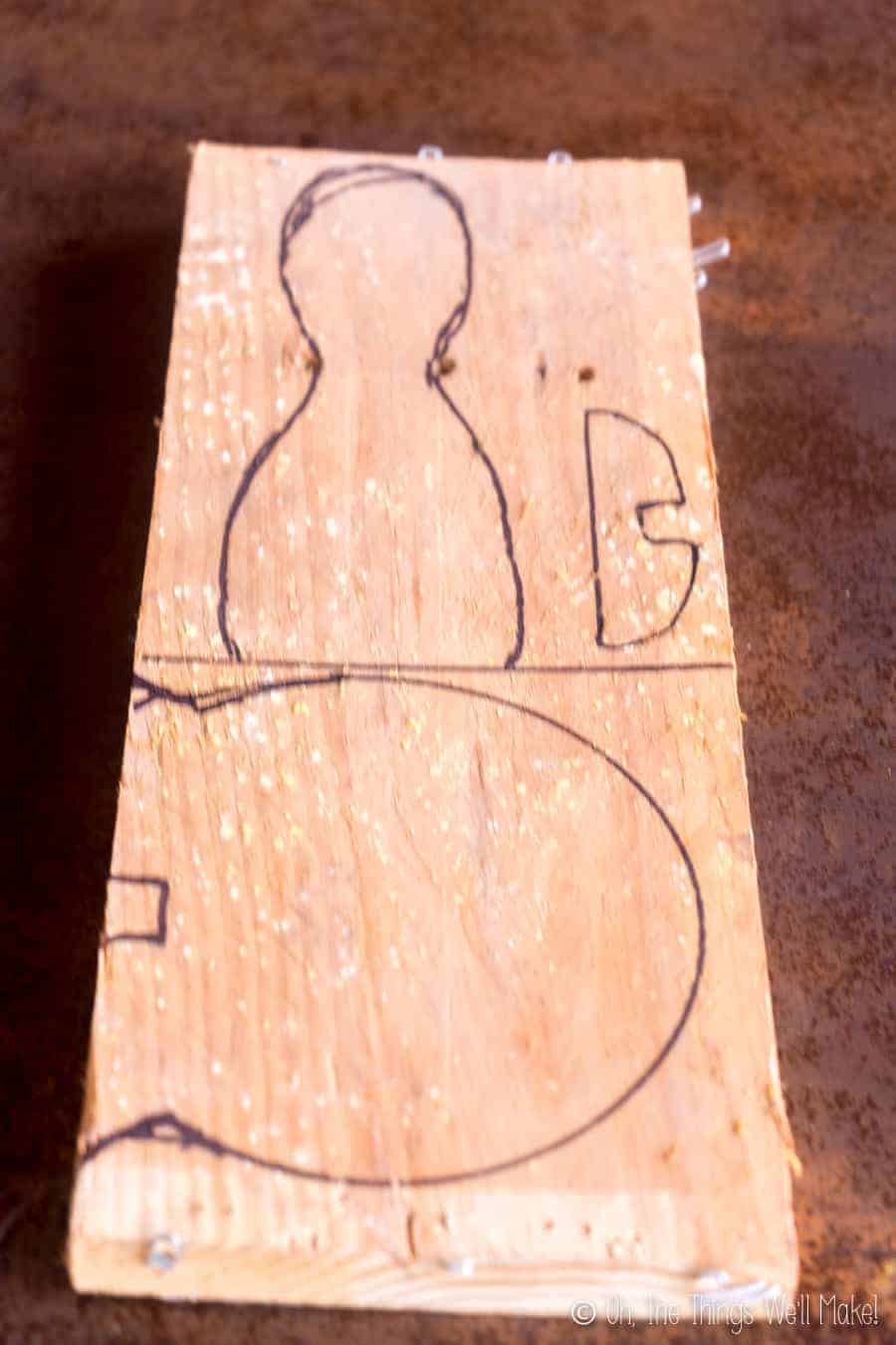 A wooden board with 3 turkey pieces drawn out on the board with black marker.