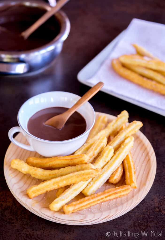 Homemade churros on a plate with a cup of Spanish hot chocolate.