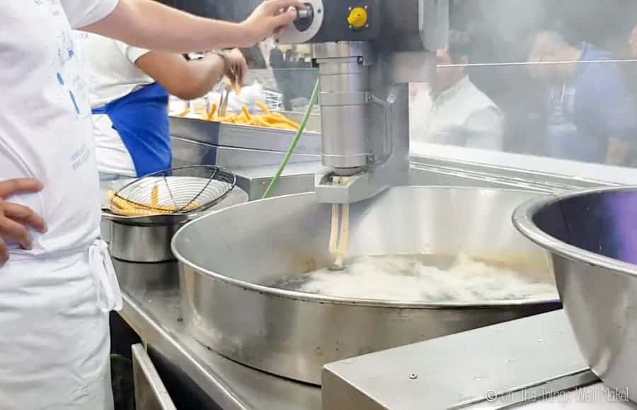 dough being dispensed into hot oil at a churros truck