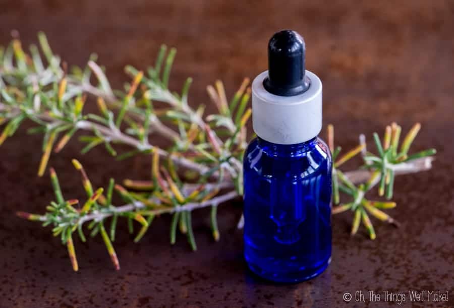 A bottle of rosemary extract in front of rosemary sprigs