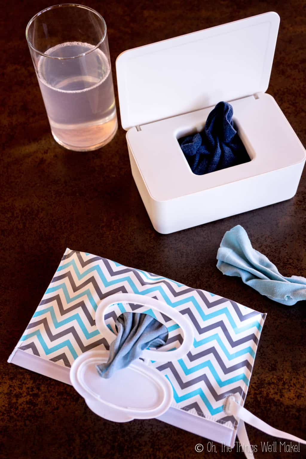 Two different wipes containers filled with homemade cloth wipes. Top container is white rectangular plastic dispenser and bottom is a chevron patterned plastic bag dispenser.