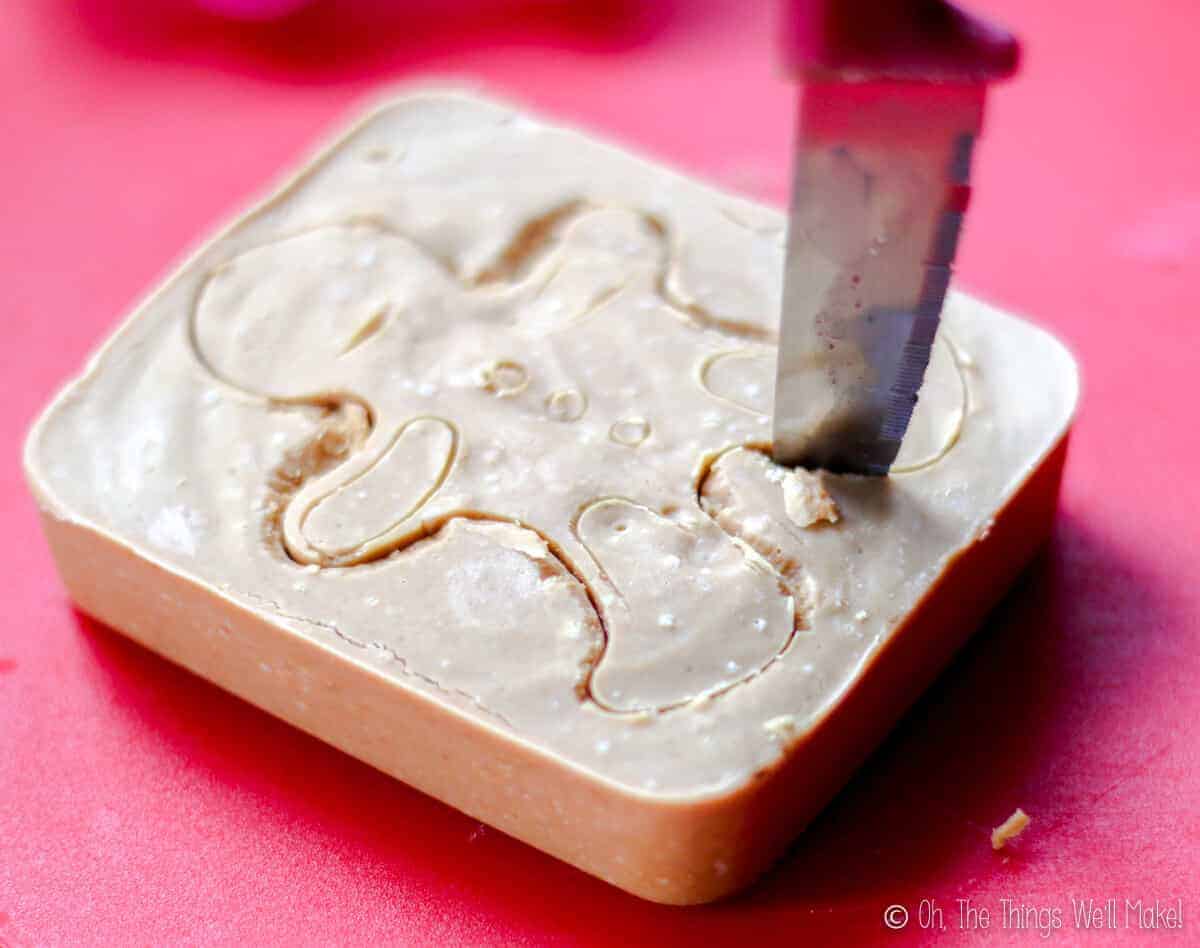 cutting out a gingerbread man shape from the soap with a knife