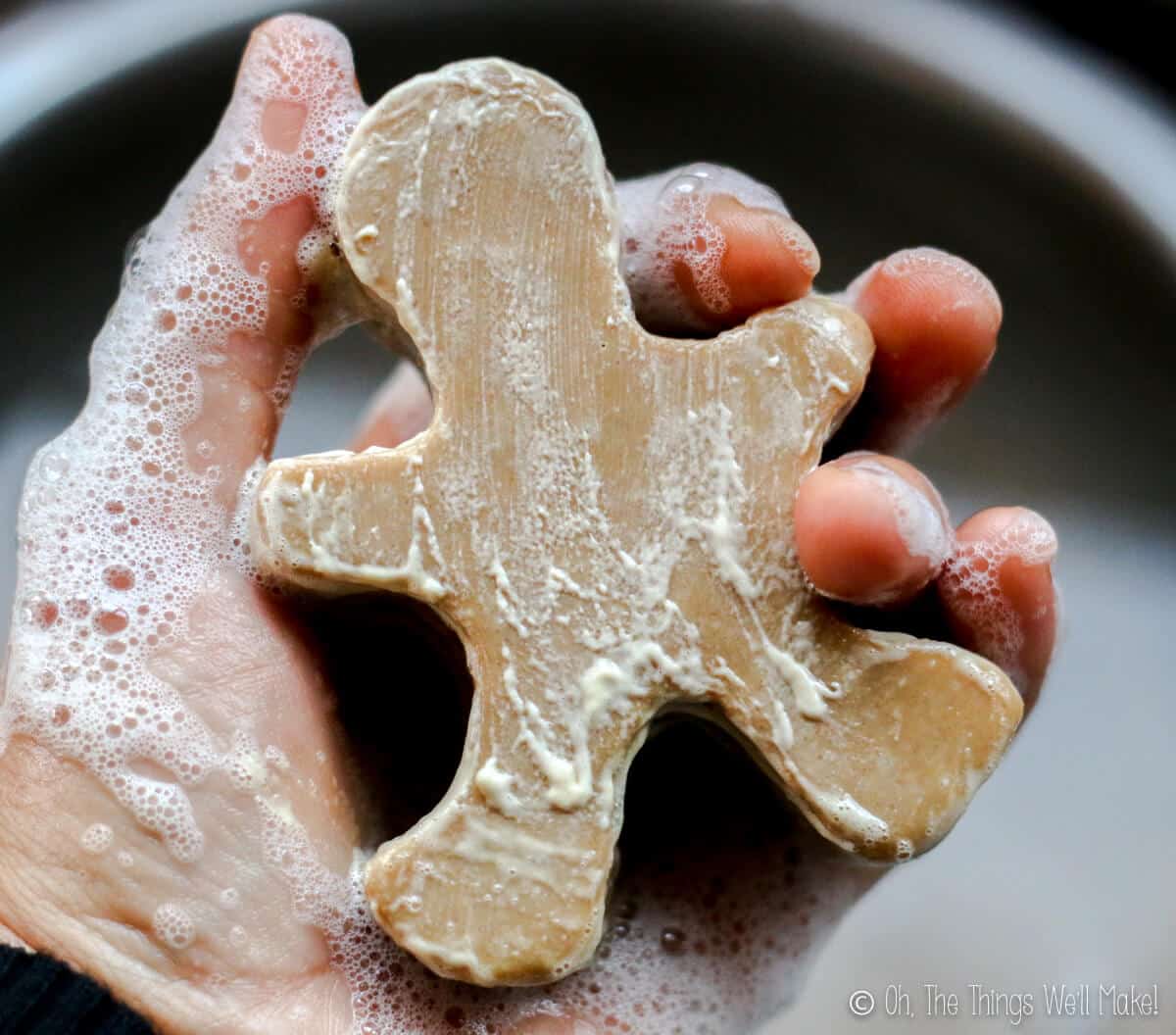 Lathering up homemade gingerbread soap that is in the shape of a gingerbread man.