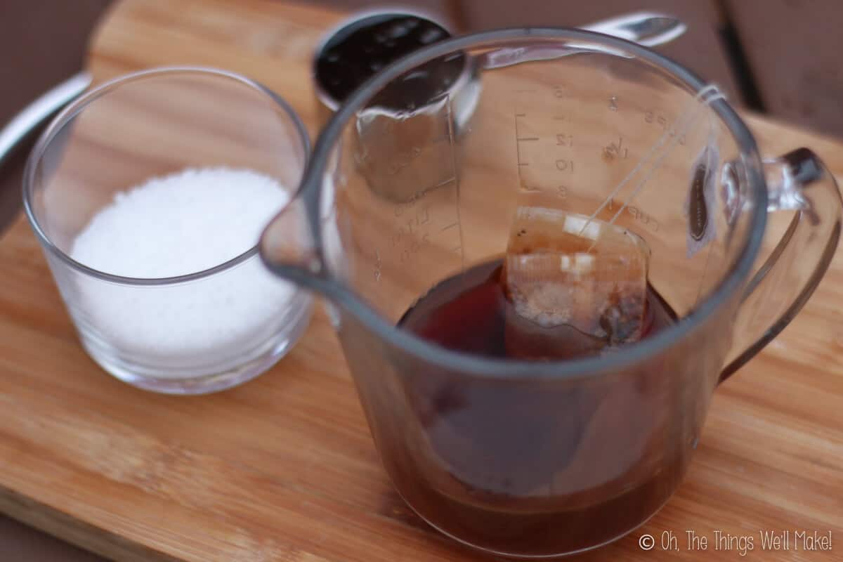Two containers, one with lye beads and another with some teabags being infused into hot water.
