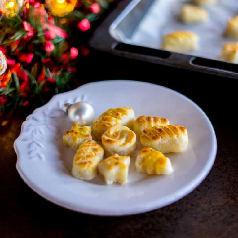 A plate full of homemade marzipan candy figures next to a baking sheet filled with them.