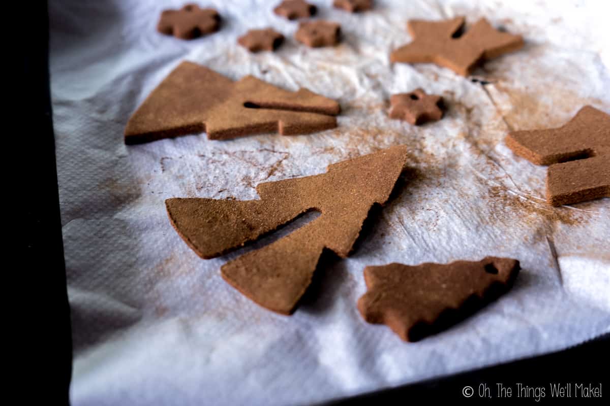 A baking sheet with several homemade cinnamon ornaments one it. One has edges that have curled upwards.
