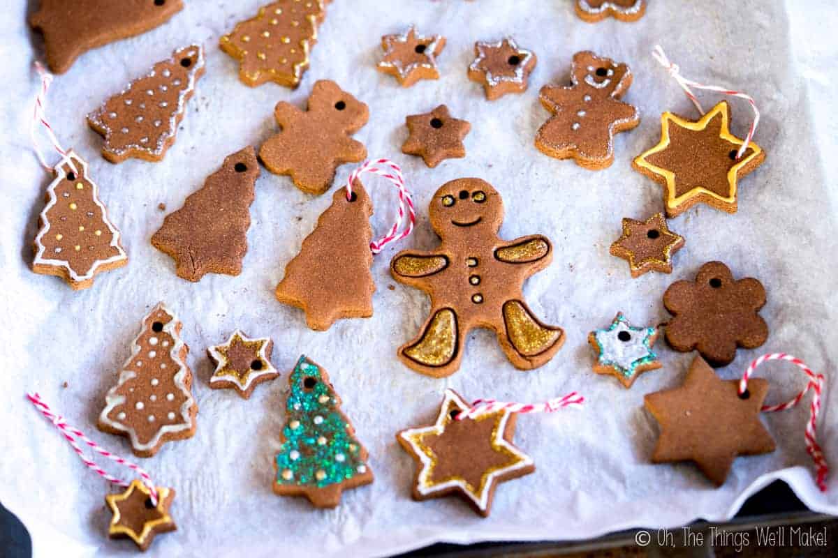 Closeup of a baking sheet filled with many cinnamon ornaments, some which have been oainted