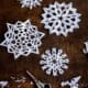 A group of homemade paper snowflakes on a counter with a pair of scissors