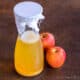 a bottle of homemade apple cider vinegar with some apples next to it.