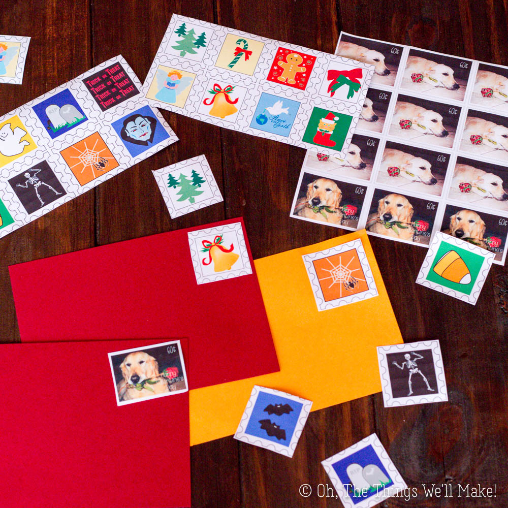 Holiday-themed postage stamps and strips arranged on a dark wooden surface with red and yellow envelopes, shown as one might make gelatin stamps.
