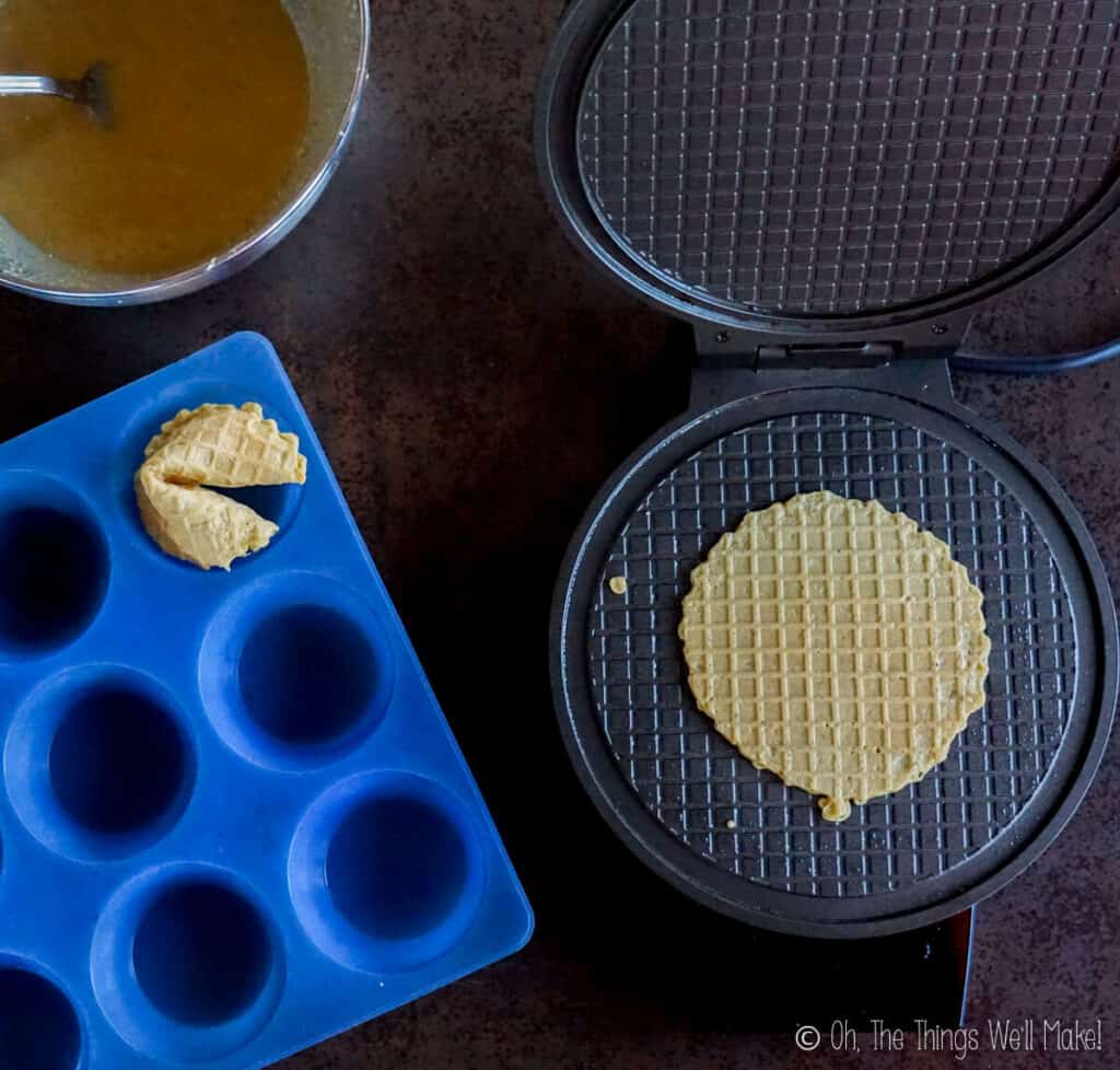 overhead view of fortune cookies being made in a pizzelle iron.