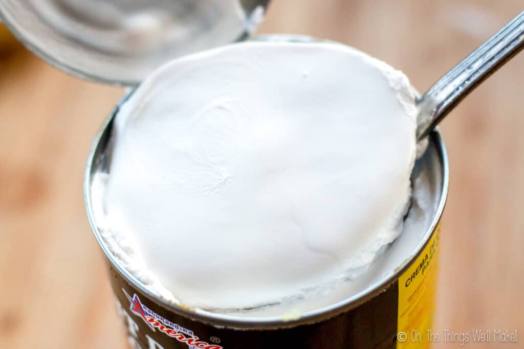 Closeup of an open can of cococnut milk that has been chilled. The top layer of coconut cream has solidified.