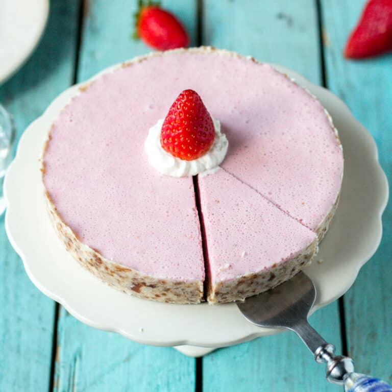 Overhead view of a paleo strawberry cream pie with one slice cut from it, ready to be removed with a spatula