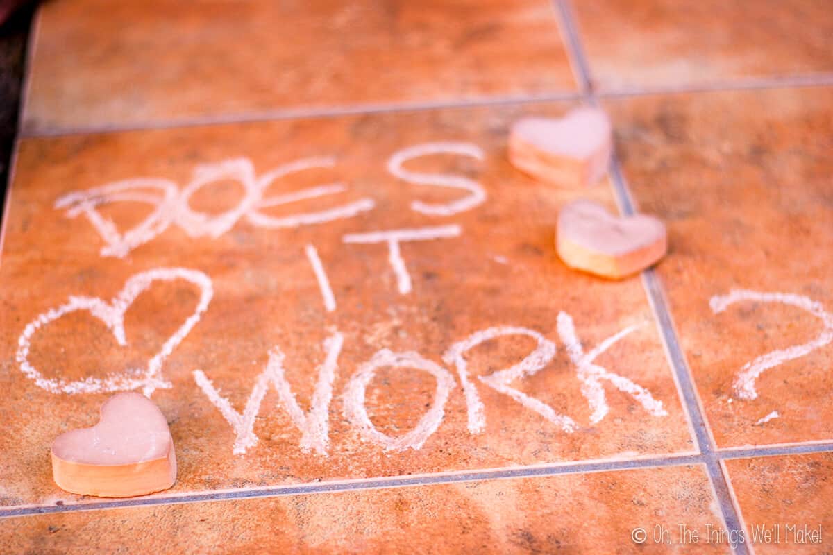 “Does it work” written on a brown tile with some pieces of heart shaped chalk laid around the writing.