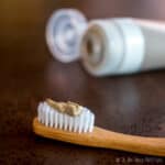 Homemade clay-based natural toothpaste (without cacao) shown on bamboo toothbrush.